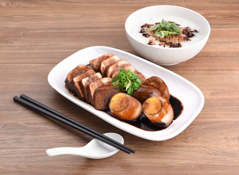 Sliced braised tofu and soy egg served with a bowl of congee