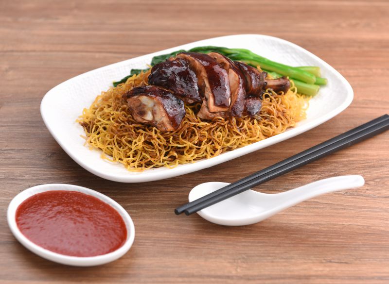 Soy sauce chicken on crispy egg noodles with choi sum and chilli sauce