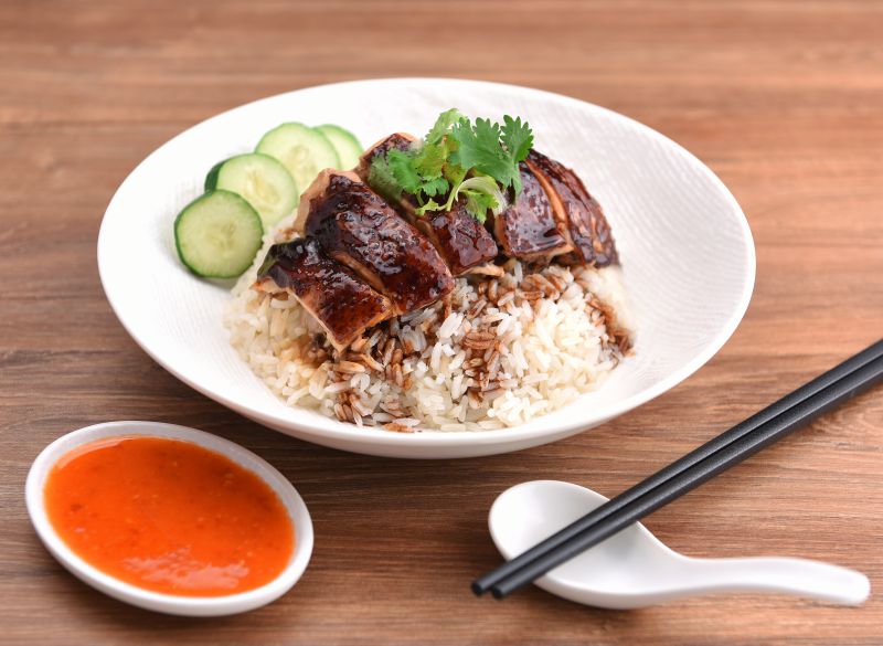 Soy sauce chicken sliced over steamed rice with cucumber and chilli sauce