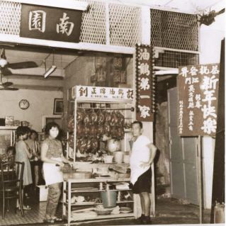 The original Chew Kee stall at Nam Yuen coffeeshop, with soy sauce chickens hanging and the founder at work