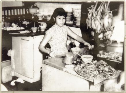 A young girl helping at the stall, preparing food behind the counter